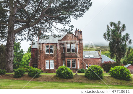 Traditional Irish cottage behind the green lawn. 47710611