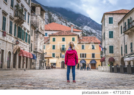 Girl in a waterproof jacket in Kotor Old Town 47710732