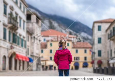 Girl in a waterproof jacket in Kotor Old Town 47710735