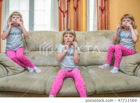 Girls playing harmonica at home Girls playing harmonica at home 47711569
