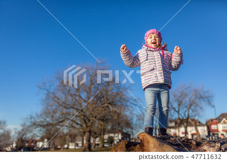 Happy girl on a large tree log Happy girl on a large tree log 47711632