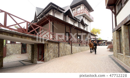 Woman leading horse into barn. Woman leading horse into barn. 47712228