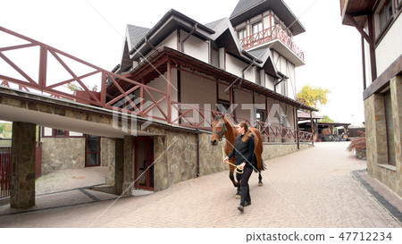 Young woman walking with horse at farm Young woman walking with horse at farm 47712234