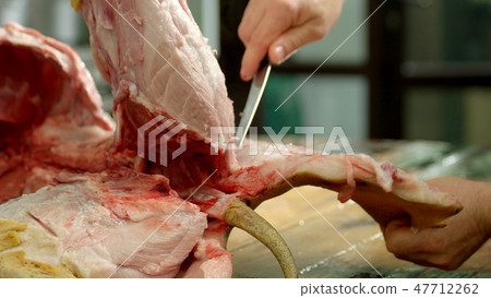 Butcher cuts pork meat in a slaughterhouse. 47712262