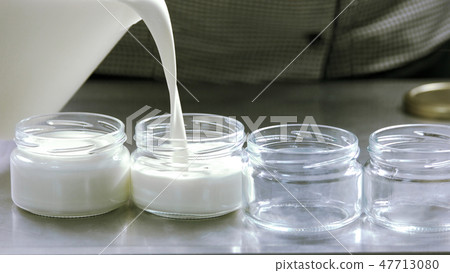 Milk pouring into glass containers. Milk pouring into glass containers. 47713080