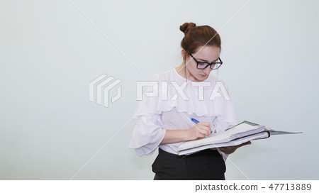 A schoolgirl in glasses depicts a successful girl with notes. A student depicts a reverie. The A schoolgirl in glasses depicts a successful girl with notes. A student depicts a reverie. The 47713889