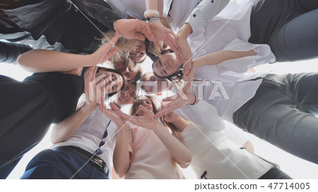 A group of high school students look through the shape of a circle created from their palms. The 47714005
