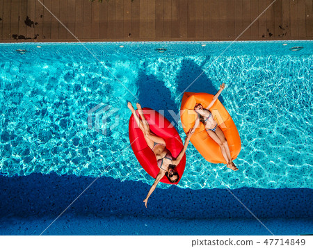 Two girls are swimming in the pool 47714849
