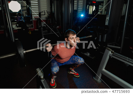 Handsome athletic man doing a squat in the gym. Handsome athletic man doing a squat in the gym. 47715693