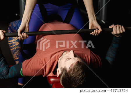 Female trainer helping guy to train in the gym Bar 47715734