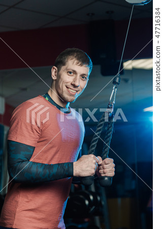 Handsome athletic man trains triceps on the block Handsome athletic man trains triceps on the block 47716384