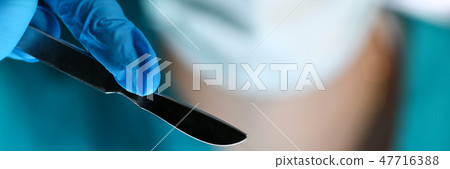 Surgeon arms in sterile uniform holding sharp knife Surgeon arms in sterile uniform holding sharp knife 47716388