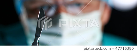 Surgeon arms in sterile uniform holding sharp knife Surgeon arms in sterile uniform holding sharp knife 47716390