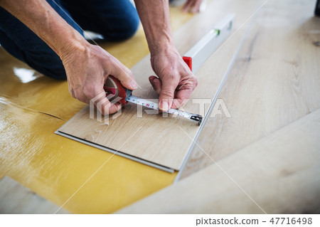 A midsection of senior man laying vinyl flooring, a new home concept. A midsection of senior man laying vinyl flooring, a new home concept. 47716498