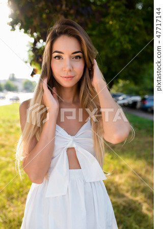 Young and beautiful girl in park with long hair. Portrait of woman summer outdoors. Tanned skin and Young and beautiful girl in park with long hair. Portrait of woman summer outdoors. Tanned skin and 47717144