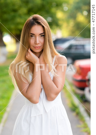 Young and beautiful girl in park with long hair. Portrait of a woman in summer outdoors. Tanned skin 47717145