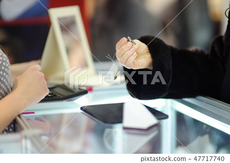 Woman choosing the perfect earrings at a jeweler Woman choosing the perfect earrings at a jeweler 47717740