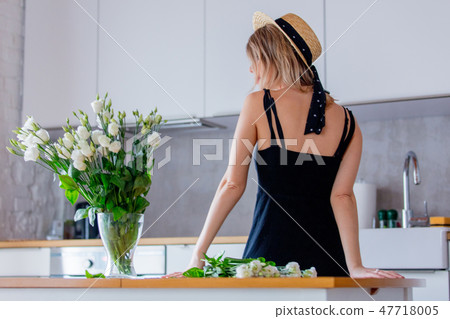 girl dressed in a black dress near white roses bouquet in a vase 47718005