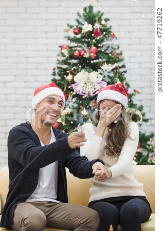 You couple sitting on sofa between christmas trees You couple sitting on sofa between christmas trees 47719262