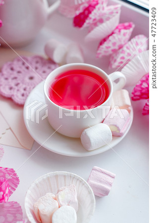A white tea cup with pink scented tea and saucer  47723409