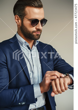 Time is money...Busy handsome businessman in stylish suit and sunglasses is checking time while 47723475