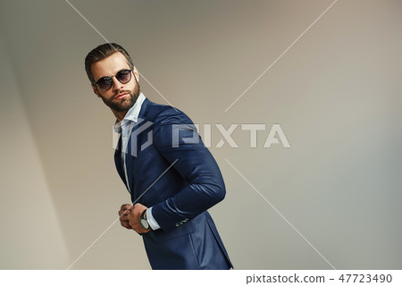 Handsome businessman at office. Bearded sexy man in a stylish suit and sunglasses is standing at 47723490