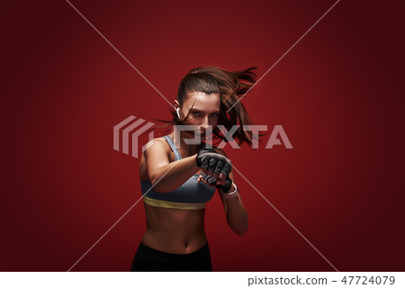 Hustle to gain more muscle. Sportswoman standing concentrated in gym gloves over red background. Hustle to gain more muscle. Sportswoman standing concentrated in gym gloves over red background. 47724079