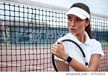 You can do it! Portrait of young beautiful woman with a racket on a court, looking away. You can do it! Portrait of young beautiful woman with a racket on a court, looking away. 47724581