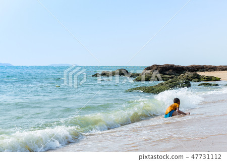 Boy playing with wave at the beach Boy playing with wave at the beach 47731112