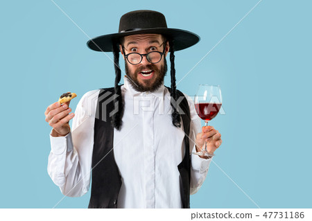 The young orthodox Jewish man with black hat with Hamantaschen cookies for Jewish festival of Purim The young orthodox Jewish man with black hat with Hamantaschen cookies for Jewish festival of Purim 47731186