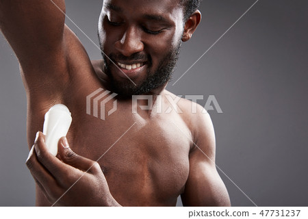 Joyful handsome afro American man using his deodorant Joyful handsome afro American man using his deodorant 47731237