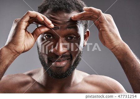 Emotional afro American man using forcepts for removing hair Emotional afro American man using forcepts for removing hair 47731254