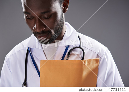 Serious afro american male doctor standing against gray background 47731311