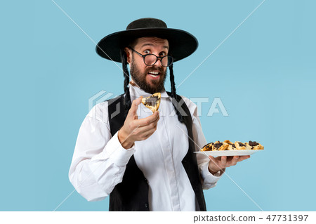 The young orthodox Jewish man with black hat with Hamantaschen cookies for Jewish festival of Purim 47731397