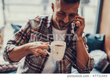Man holding cup of beverage and speaking on telephone 47731443