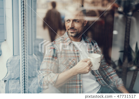 Man with cup of tea looking on the street 47731517