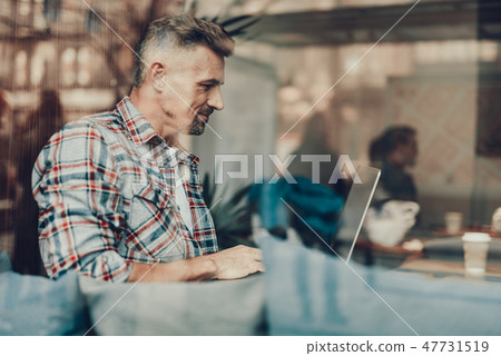 Attractive man using laptop while sitting in cafe Attractive man using laptop while sitting in cafe 47731519