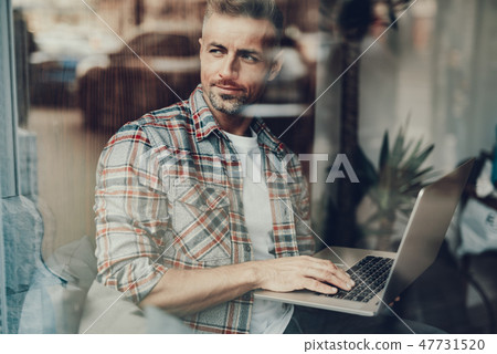 Man using netbook and looking through window on street 47731520