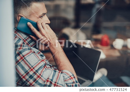 Man holding telephone near face and speaking with friends Man holding telephone near face and speaking with friends 47731524