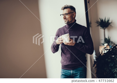 Attractive man holding cup of tea and smiling Attractive man holding cup of tea and smiling 47731662
