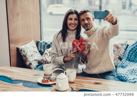 Two person sitting in cafe with present and making selfie Two person sitting in cafe with present and making selfie 47732099