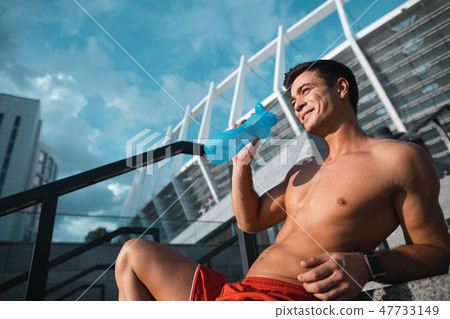 Cheerful stripped to waist man tasting liquid 47733149