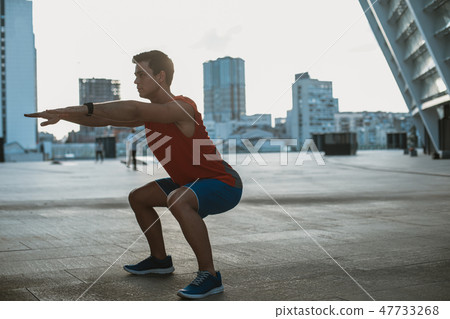 Focused male athlete making physical exercise outdoor 47733268
