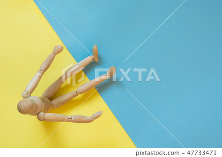 Wooden doll on yellow and blue. Concept beach sand and water. 47733471