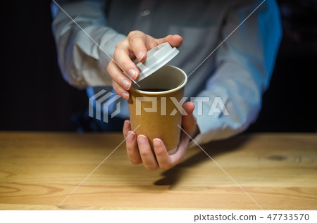 Barista serves coffee in a paper cup at the bar 47733570