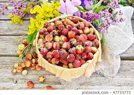 Strawberries in box with flowers on old board Strawberries in box with flowers on old board 47733773