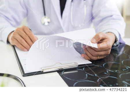 The doctor performs working writing on paperwork and analysis of The doctor performs working writing on paperwork and analysis of 47734221