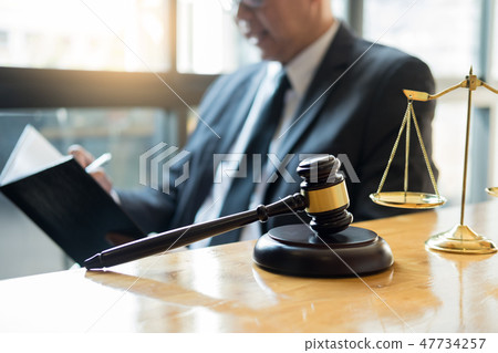 Male lawyer working with contract papers and reading law book in 47734257