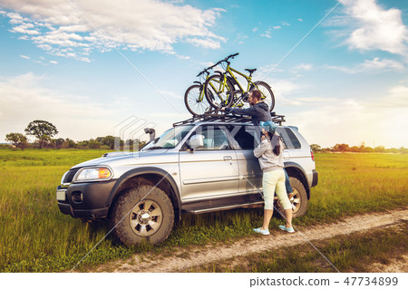 Couple taking off their bicycles from roof rack 47734899