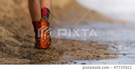 Athlete runner running on waves of sea beach 47735922